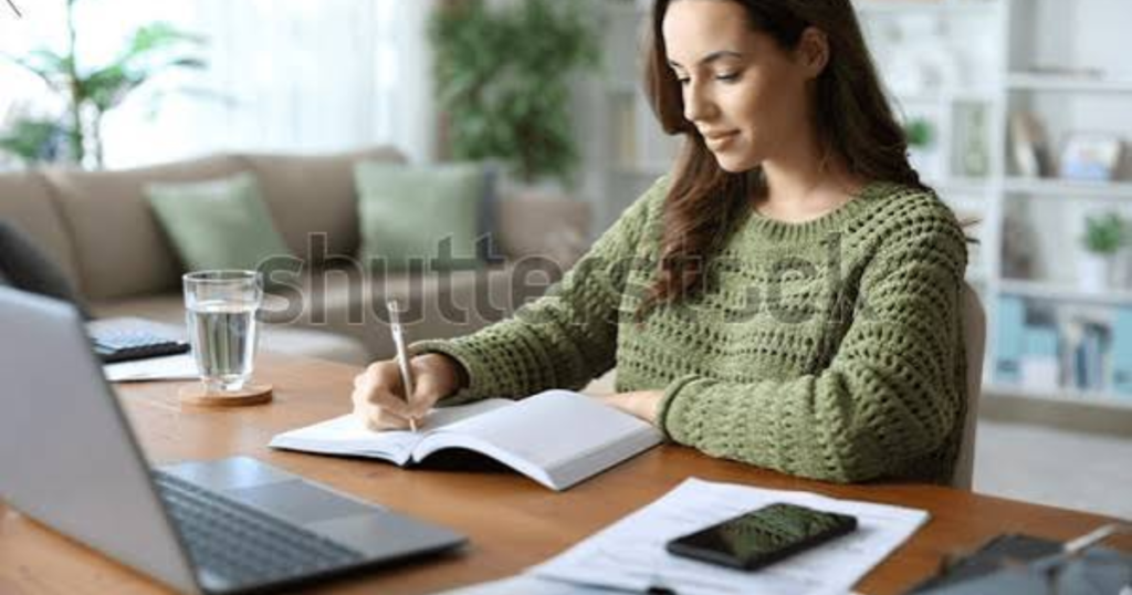 Professional writing goals in a notebook beside a laptop on a bright desk
