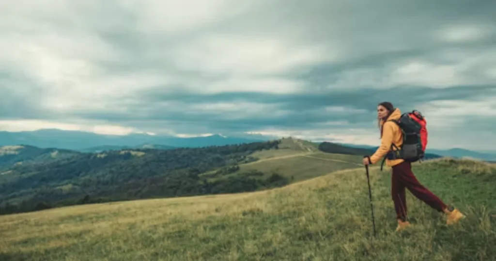 Hiker looking toward distant mountains at sunrise, representing ambition and long-term goals
