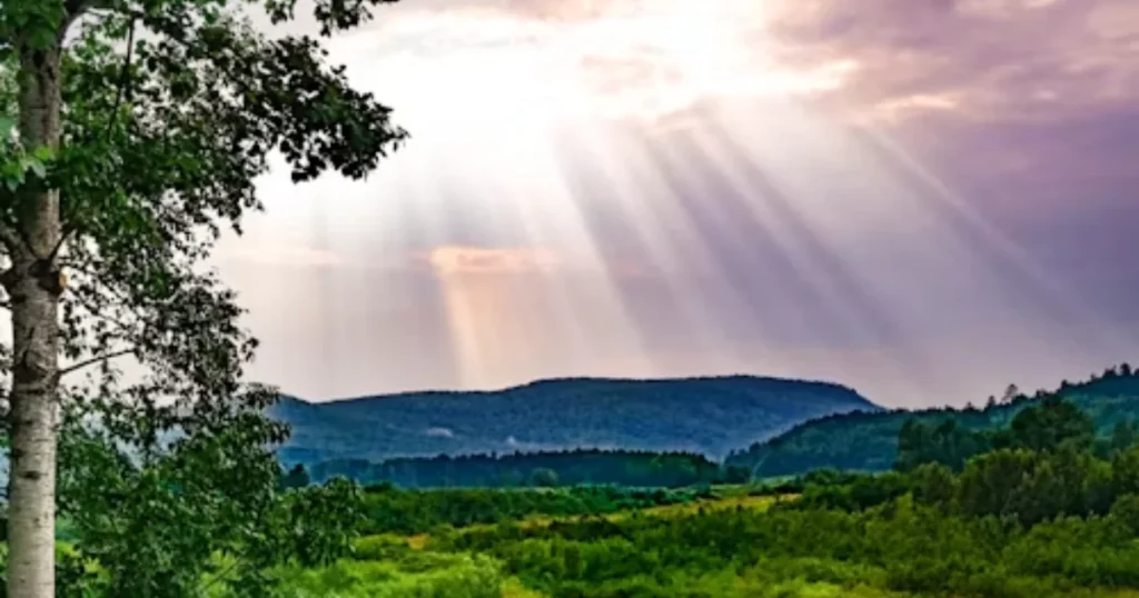 Sunlight breaking through clouds over a peaceful landscape in Motivational Quotes
