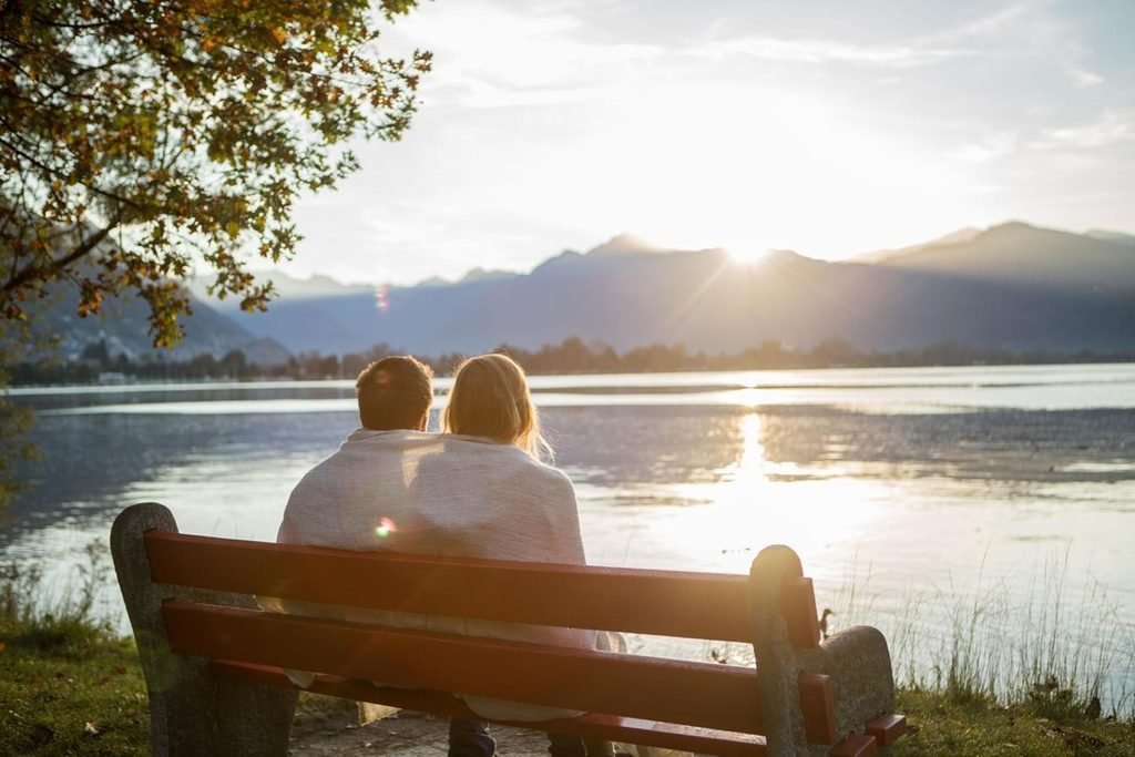 Couple sitting together beside a peaceful lake, representing healing and a fresh start.
